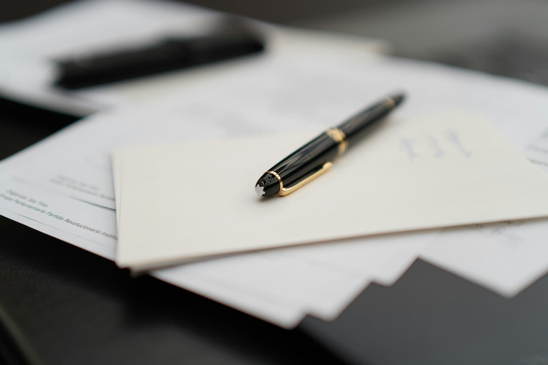 A fountain pen resting on a stack of papers