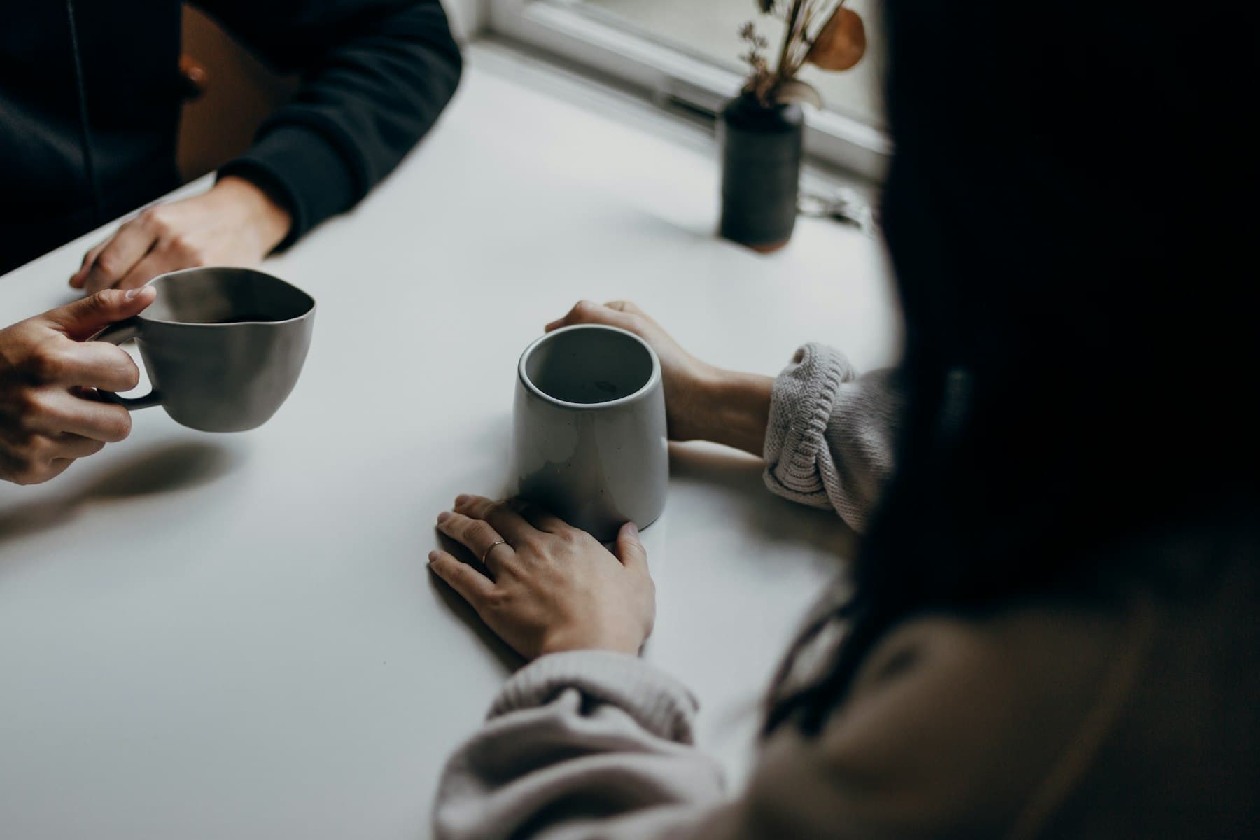 Two people talking over coffee at a kitchen table
